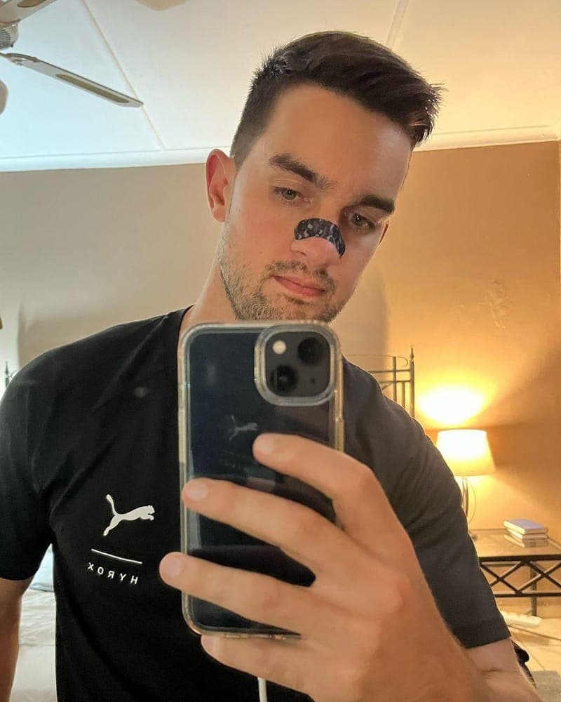Man taking a mirror selfie wearing a RestUp nasal strip